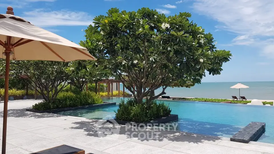 Luxurious beachfront pool with lush greenery and ocean view, perfect for relaxation and leisure.