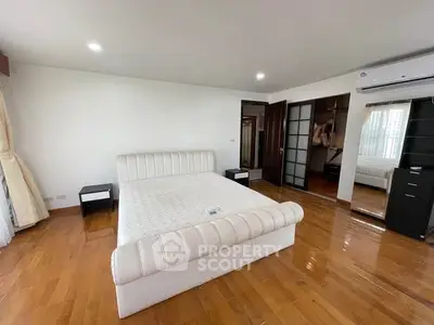 Spacious bedroom with wooden flooring and modern furnishings in a luxury apartment.