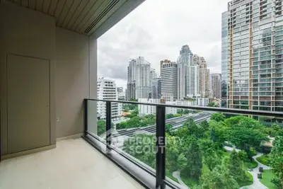 Stunning cityscape view from modern high-rise balcony overlooking lush green park.