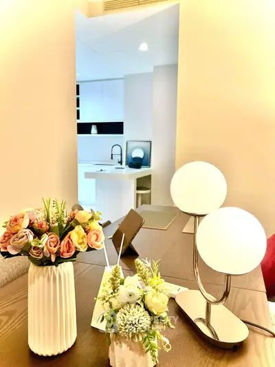 Modern interior with elegant decor and open kitchen layout, featuring stylish lighting and floral arrangements.