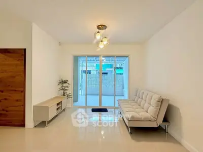 Spacious living room with modern sofa and sliding glass doors leading to a bright balcony.