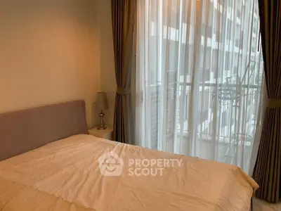 Cozy bedroom with large window and sheer curtains in modern apartment