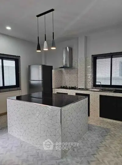 Modern kitchen with sleek island and gas stove, featuring stylish pendant lighting and contemporary design.