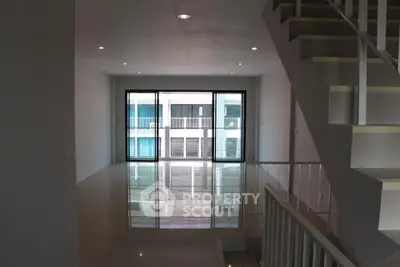 Modern interior with sleek staircase and large windows offering natural light and urban views.