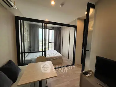 Modern studio apartment with glass partitioned bedroom and cozy living area.