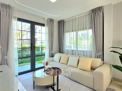 Elegant living room with large windows and modern decor, offering a bright and inviting atmosphere.