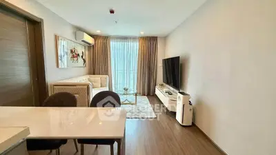 Modern living room with stylish decor and large TV, featuring natural light and elegant furnishings.