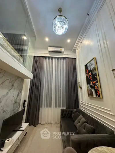 Luxurious living room with high ceiling, elegant decor, and modern chandelier