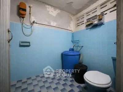 Compact bathroom with blue tiles and basic amenities in need of renovation.