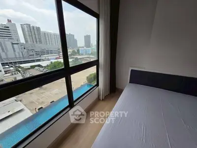 Modern bedroom with large window offering city view in high-rise apartment