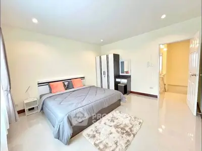 Spacious bedroom with modern decor and ensuite bathroom in a bright, airy apartment.