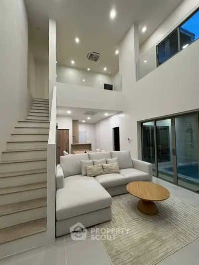 Spacious modern living room with high ceilings and elegant staircase in a luxurious home.