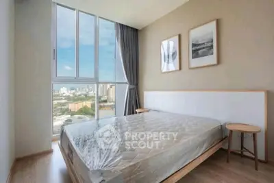 Modern bedroom with large window offering stunning city view, featuring minimalist decor and natural light.