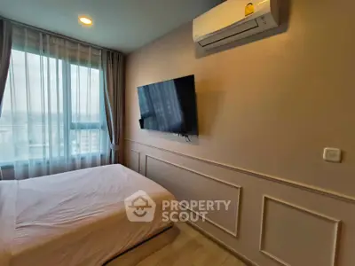 Modern bedroom with wall-mounted TV and large window offering city views.