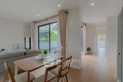 Spacious modern living room with dining area and large windows offering natural light and garden view.