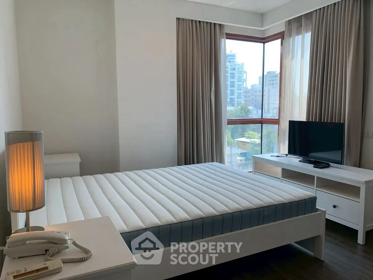 Bright and modern bedroom with large windows and city view, featuring a comfortable bed and sleek furnishings.