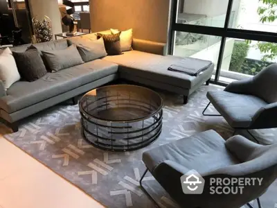 Spacious and modern living room with large sectional sofa, stylish armchair, and unique round coffee table, complemented by elegant patterned rug and natural light.