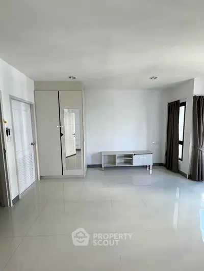 Spacious unfurnished living room with large windows and modern tile flooring.