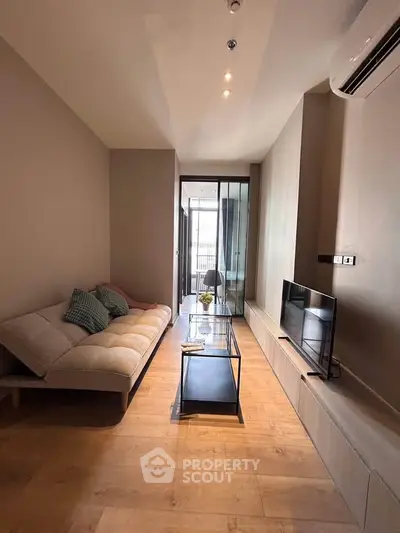 Modern living room with sleek design, featuring a cozy sofa, glass coffee table, and wall-mounted TV.