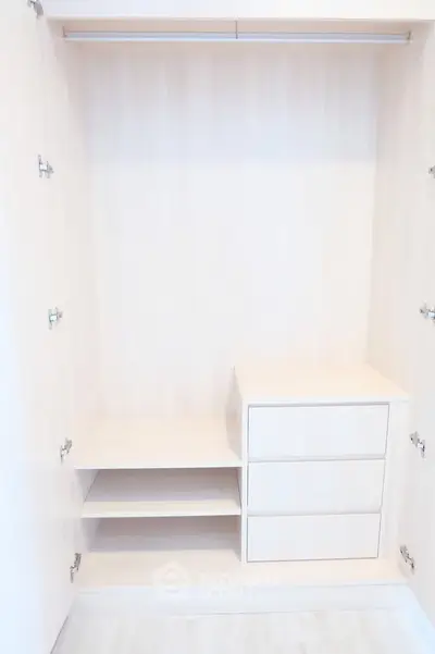 Spacious walk-in closet with built-in shelves and drawers, perfect for organized storage.