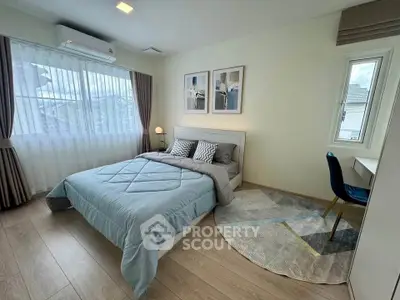 Modern bedroom with stylish decor, large window, and cozy bed in a bright, airy space.