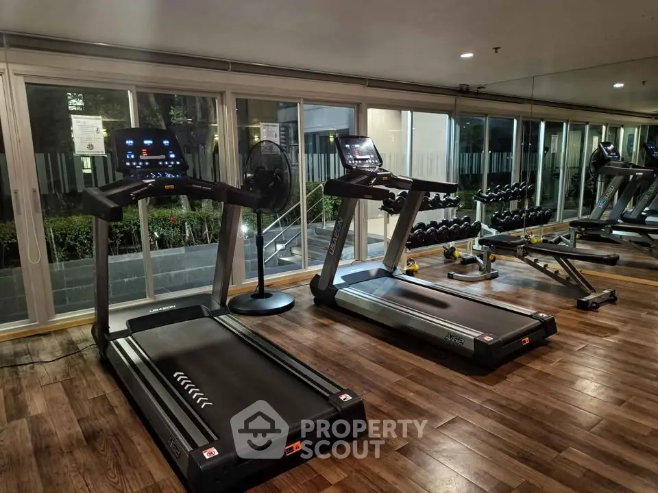 Modern gym with treadmills and weights in a well-lit fitness center