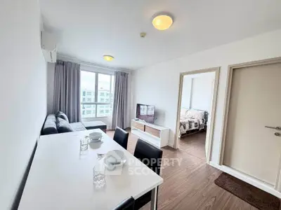 Modern living room with dining area, featuring sleek furniture and large windows for natural light.