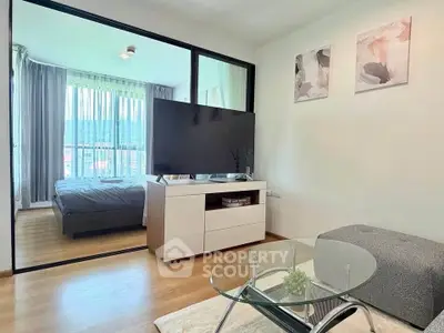 Modern living room with glass coffee table and view into cozy bedroom