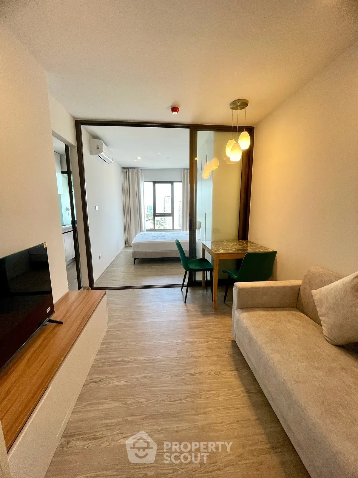 Modern studio apartment with open layout, featuring cozy living area and stylish bedroom separated by glass partition.