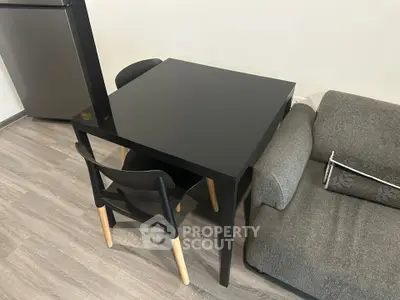 Modern living room with sleek black dining table and cozy gray sofa, perfect for urban living.