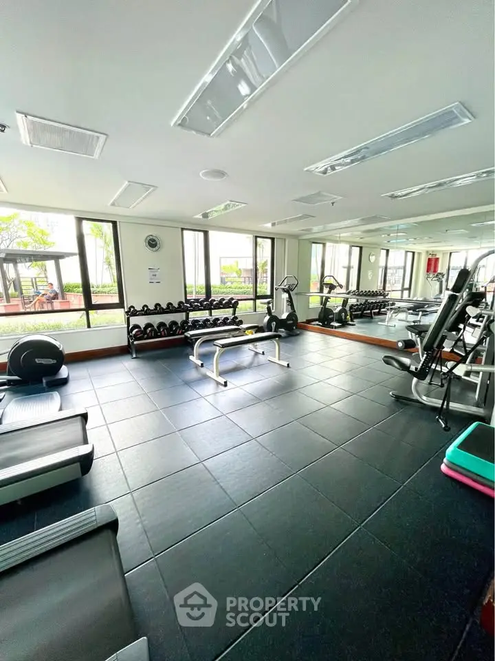 Spacious gym with modern equipment and large windows in a residential building.