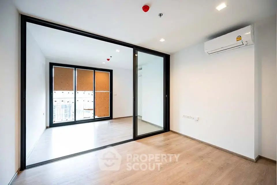 Spacious modern living room with large glass doors and air conditioning, perfect for urban living.
