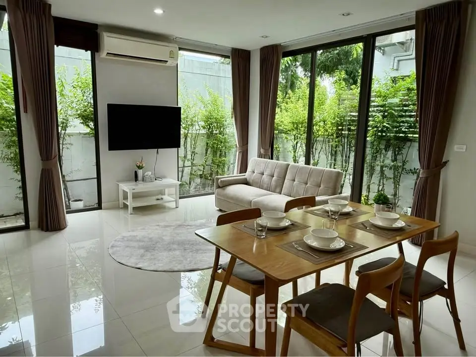 Modern living room with large windows and stylish dining area, perfect for entertaining.