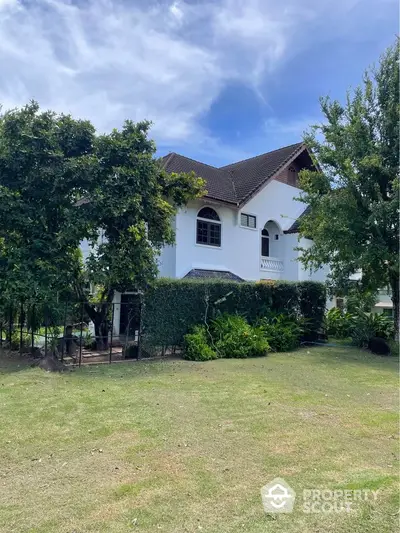 Charming two-story house with lush garden and spacious lawn, perfect for family living.