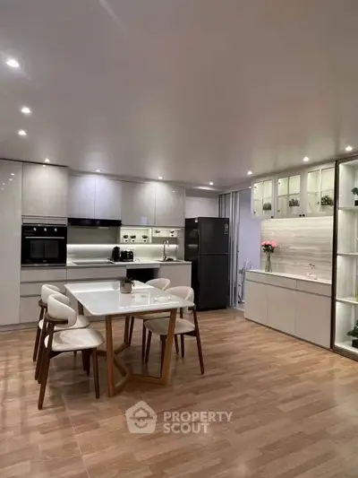 Modern kitchen with sleek design, featuring built-in oven, spacious fridge, and elegant dining area.