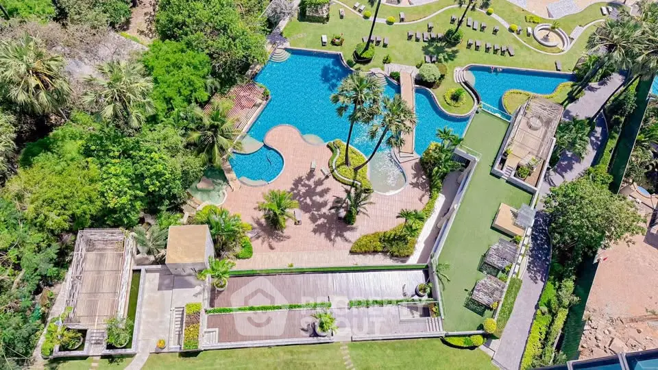 Luxurious aerial view of a resort-style pool with lush landscaping and sun loungers.