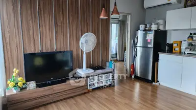 Modern living room with wooden flooring, stylish TV unit, and compact kitchen area.