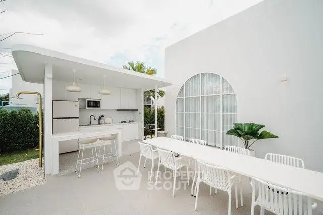 Modern outdoor kitchen with sleek white design and spacious dining area