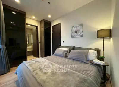 Luxurious bedroom with modern decor and ensuite bathroom in upscale apartment.