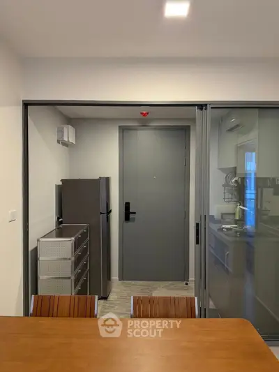 Modern kitchen with sleek appliances and dining area in contemporary apartment.