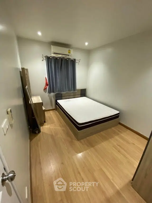 Cozy bedroom with polished wooden flooring, a large comfortable bed, and modern air conditioning, perfect for restful nights in a serene environment.