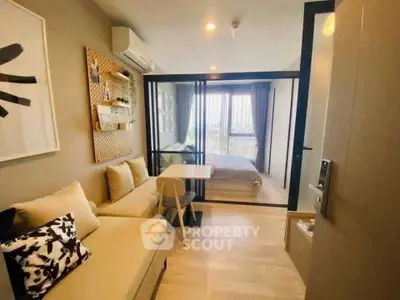 Modern apartment with cozy living room and glass-walled bedroom, featuring stylish decor and natural light.