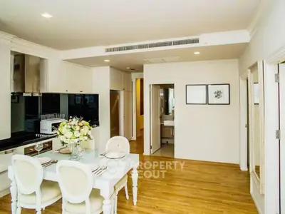 Elegant dining area with modern kitchen in a stylish apartment, featuring hardwood floors and chic decor.