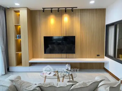 Modern living room with stylish wood paneling and mounted TV, featuring cozy seating and elegant decor.
