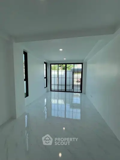 Spacious modern living room with large windows and glossy marble flooring.