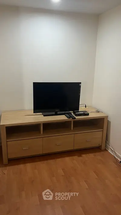 Modern living room with sleek wooden TV stand and flat-screen television.