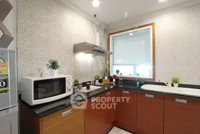 Modern kitchen with sleek cabinets, microwave, and window for natural light.