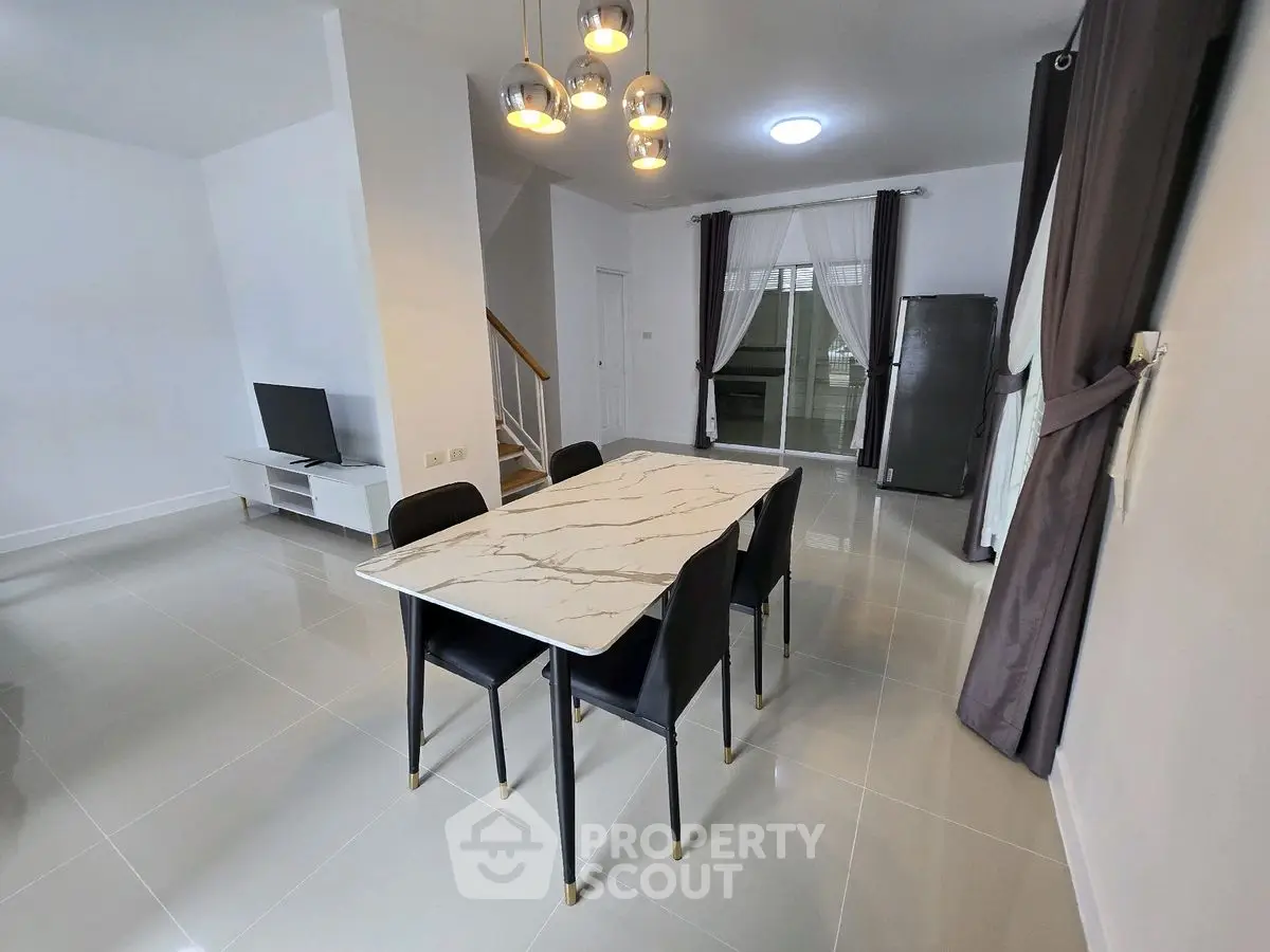 Modern dining area with marble table and sleek black chairs in a stylish open-plan living space.