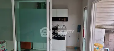 Compact kitchen with sliding glass door and modern appliances in cozy apartment.