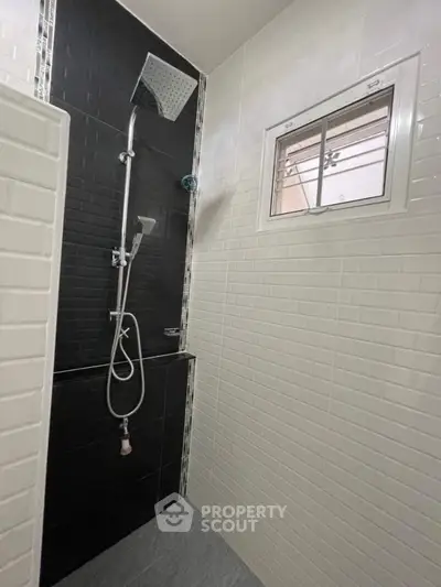 Modern bathroom with sleek black and white tiles and a rainfall showerhead.